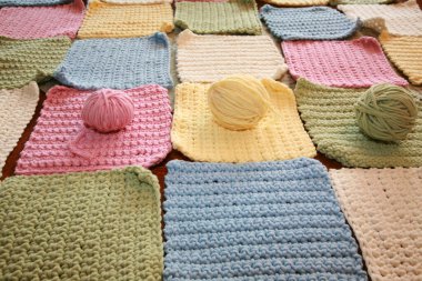 İplik. El yapımı renkli örülü battaniye. El yapımı örgü kareler ve bebek battaniyesine dikilmeye hazır iplikler. Örgü ya da örgü kareler. Örgü örmek için çeşitli ve parlak renkli iplikler. Yaratıcılık ve iğne işi için mallar. Örgü örüyorum. Düğüm