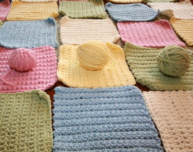 İplik. El yapımı renkli örülü battaniye. El yapımı örgü kareler ve bebek battaniyesine dikilmeye hazır iplikler. Örgü ya da örgü kareler. Örgü örmek için çeşitli ve parlak renkli iplikler. Yaratıcılık ve iğne işi için mallar. Örgü örüyorum. Düğüm