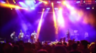 Canlı müzik etkinliği. Konserde kalabalık el kaldırıyor ve arka planda parlak sahne ışıkları var.,