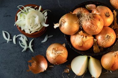 Tezgahta bir kase soğan ve bir kase doğranmış soğan duruyor. Soğanlar doğramanın çeşitli aşamalarındadır., 