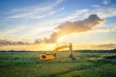 Bir yaz akşamında gün batımında yeşil bir tarlada tekerlek yükleyici
