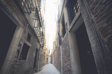 İtalya 'da Venedik' te küçük bir sokak geçidi var. Pencerelerinde uzun grunge binalar ve parmaklıklar var.