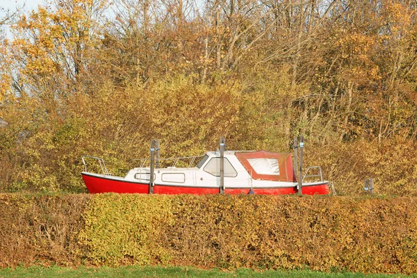Fishing boat on shore in the off season in the fall with colorful trees