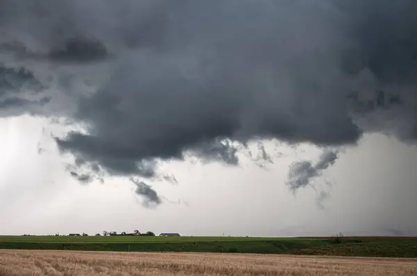 低い壁の雲が厳しい嵐の下に集まり その下には農場がある — ストック写真