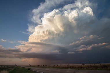 Güneş ışığı, aşağıdaki çayırlara çok ihtiyaç duyulan yağmuru yağdıran kümülonimbus bulutunun üzerinde parlıyor..