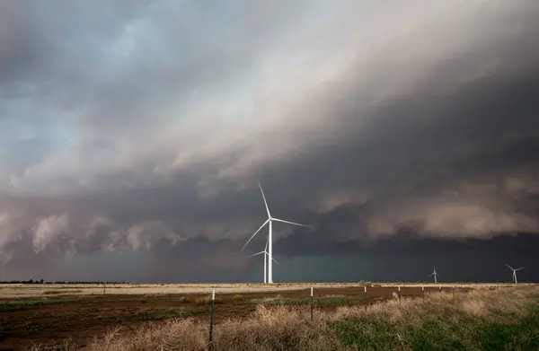 風力タービンは平らな風景の上に立って 地平線上に迫っている暗い嵐雲 — ストック写真