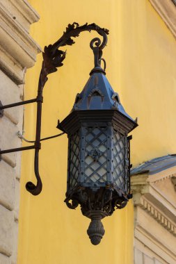 Siyah metalden yapılmış eski moda sokak lambası. Penceresi ve ahşap çerçevesi olan eski bir evin gri cephesi. Lviv, Ukrayna.