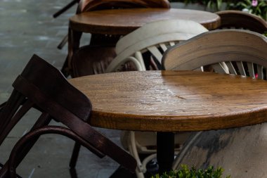 Islak, boş masa ve yağmur sırasında açık hava kafeteryasının terasında sandalyeler. Yağmur altında sokak şehri hayatı.