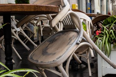 Islak, boş masa ve yağmur sırasında açık hava kafeteryasının terasında sandalyeler. Yağmur altında sokak şehri hayatı.