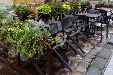 Islak, boş masa ve yağmur sırasında açık hava kafeteryasının terasında sandalyeler. Yağmur altında sokak şehri hayatı.