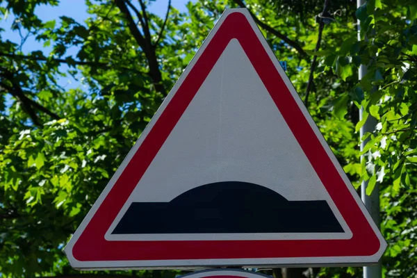 Triangular warning road sign Hump in the road beautiful blue cloudy sky.