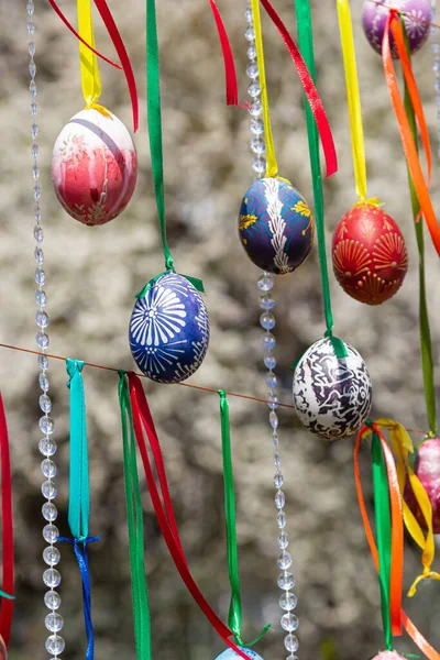 stock image Painted eggs hang from the branches of the Easter tree. The focus is on a yellow egg painted by children by hand. High quality photo