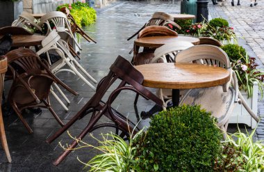 Islak, boş masa ve yağmur sırasında açık hava kafeteryasının terasında sandalyeler. Yağmur altında sokak şehri hayatı.
