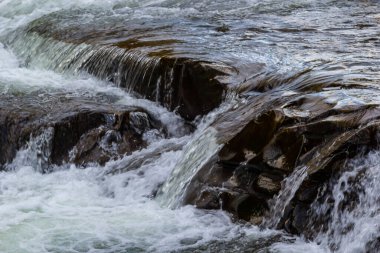 Kayaların üzerinden akan su akıntısı. Görüntüyü yaklaştır..