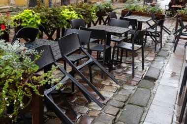 Islak, boş masa ve yağmur sırasında açık hava kafeteryasının terasında sandalyeler. Yağmur altında sokak şehri hayatı.