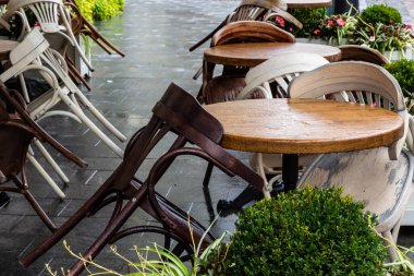 Islak, boş masa ve yağmur sırasında açık hava kafeteryasının terasında sandalyeler. Yağmur altında sokak şehri hayatı.