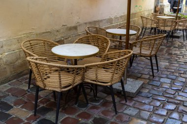 Islak, boş masa ve yağmur sırasında açık hava kafeteryasının terasında sandalyeler. Yağmur altında sokak şehri hayatı.