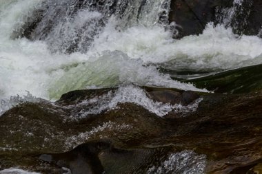 Nehir torrentinin üstündeki soyut dokuya yakın çekim ve güneşli bir günde vadideki kayalıklarda köpük ve kabarcıklarla akan temiz soğuk su. Doğa gücü ve güç arkaplanı.