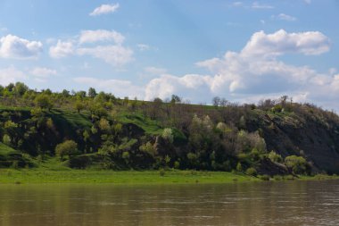 View of the Dniester River in spring. The river surrounds the mountain slopes covered with lush, bright green vegetation.
