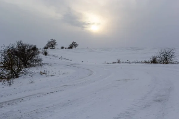 日没時に雪に覆われた田園地帯を通る道路 晴れた冬の日 — ストック写真