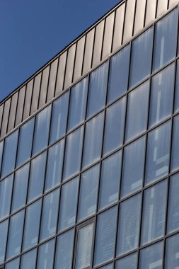 Promosyon içeriği için gökyüzü arka planında cam penceresi olan modern bir gökdelen binasının alt manzarası. Yeni perspektif tasarımlı çağdaş iş merkezi.