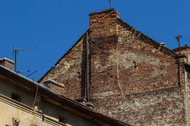 Pencereli kırmızı tuğla duvar. Gökyüzünün arka planında bulutlu alt görünüm.