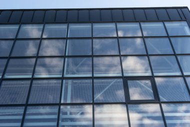 Promosyon içeriği için gökyüzü arka planında cam penceresi olan modern bir gökdelen binasının alt manzarası. Yeni perspektif tasarımlı çağdaş iş merkezi.