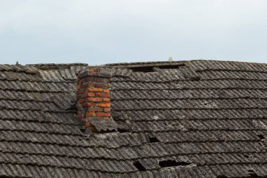Köy evinin tepesindeki kırmızı tuğladan baca. Gökyüzünün arka planında fayanslardan yapılmış bir çatı.