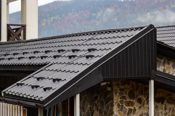 新しい茶色の金属タイルの屋根と雨のガター付きの家 金属ゲーターシステム ゲーターおよび排水管外観 — ストック写真