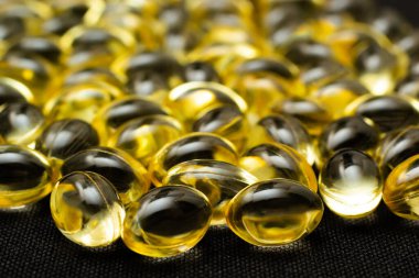 Omega 3 jel kapsülünü yansıtıcı siyah arka planda kapat.