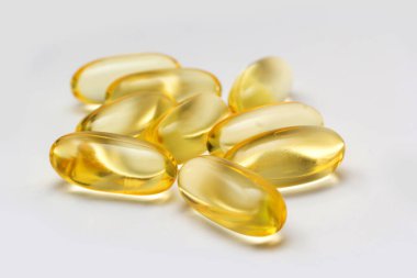 Açık arkaplanda balık yağı kapsülleri Omega 3. Balık yağının saydam sarı kapsülleri.