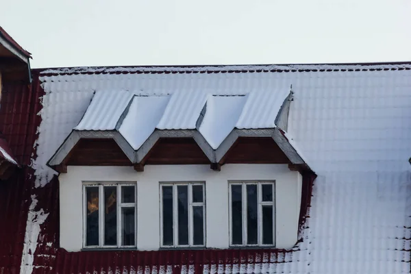 窓のあるヨーロッパの家の赤 茶色の金属製の屋根の上の雪 — ストック写真