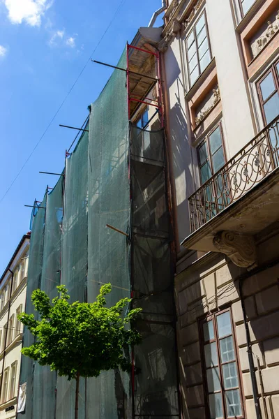 Restoration of the building. Scaffolding and protective green building mesh. Safety techniques during construction works.