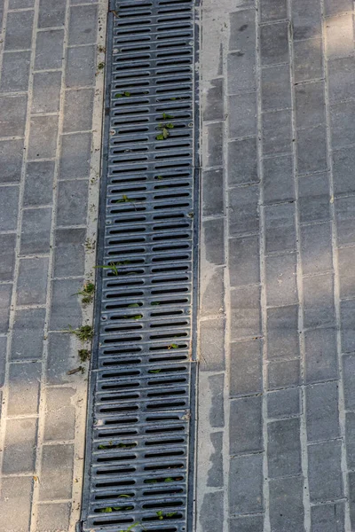 正方形の石瓦で作られた歩道上の排水路舗装システムの格子 雨水排水システムの閉鎖 — ストック写真