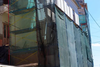 Binanın restorasyonu. İskele ve koruyucu yeşil bina örgüsü. İnşaat sırasında güvenlik teknikleri.