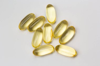 Açık arkaplanda balık yağı kapsülleri Omega 3. Balık yağının saydam sarı kapsülleri.