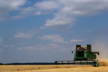 Havadaki toz samanıyla buğday toplayan hasat makinesinin fotoğrafı..