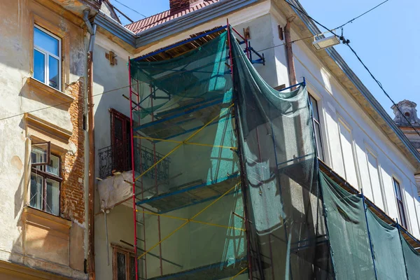 Restoration of the building. Scaffolding and protective green building mesh. Safety techniques during construction works.