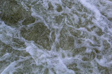 Şiddetli beyaz su nehrinin ayrıntıları açık yeşil renkli bir nehirden akarak dokulu bir zemin oluşturur..