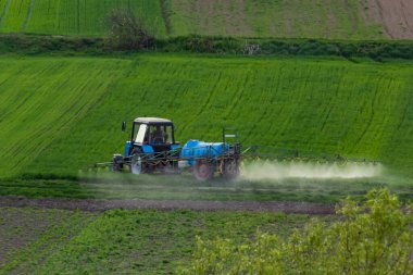 Kırpma yeşil çiftlik alanlarındaki pestisit ile püskürtme traktörün havadan görünümü.
