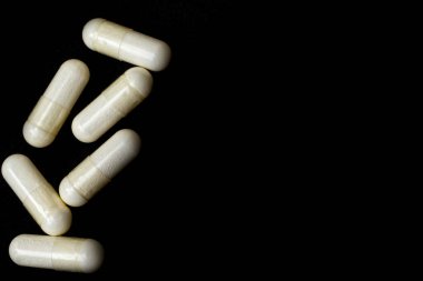 Beyaz kapsüller, siyah arka planda metne uygun haplar. Tıp, sağlık hizmeti konsepti. Eczacılık ilaçlarının aralığı.