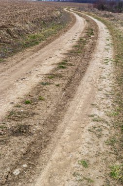 Kırık ülke toprak yol ile lots-in yağmur sonra çamurlu su birikintileri bahar dağlarda.