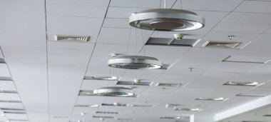 Çağdaş ofis ortamında tavan tasarımı, çalışma alanının estetik ve işlevselliğini artıran parlak ışık ve havalandırma delikleri içeriyor..