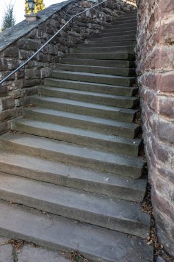 Sağlam taş basamaklar, yıpranmış bir kaya duvarıyla çevrili bir yamaçtan yükselir, ziyaretçileri doğal çevreyi keşfetmeye ve panoramik manzaranın tadını çıkarmaya davet eder..