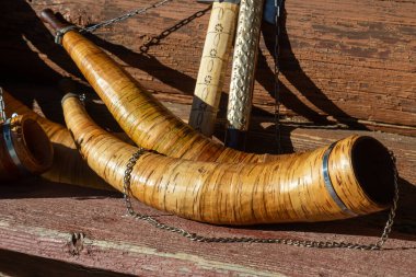 Tahtadan yapılmış boynuz enstrümanları ve yıpranmış ahşap bir yüzey üzerinde metal detaylarıyla süslenmiş, sonbahar fuarında bir zanaatkarlık sergiliyor..