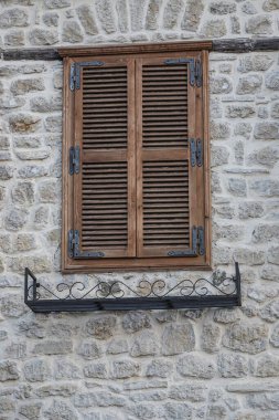 Geleneksel ahşap panjurlar Arnavutluk 'ta kırsal taştan bir duvar süsleyerek, gün ışığında eşsiz işçilik ve mimari ayrıntılar sergiliyor.