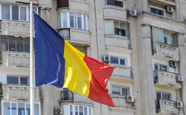 Bükreş 'teki bir konut binasının önünde belirgin bir şekilde sergilenen, rüzgarda dalgalanan canlı bir Romen bayrağı kentin ruhunu yansıtıyor.