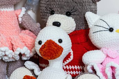 Bir ayı, bir ördek ve bir kedi içeren pelüş oyuncaklar koleksiyonu, canlı renklerini sergiliyor ve yumuşak bir arkaplana karşı karmaşık detaylar veriyor..