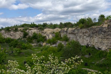 Yeşillik eski bir taş ocağının yamaçlarını kaplıyor. Dik uçurumlar dinamik bulutların zeminine yükseliyor ve dingin bir doğal ortam yaratıyor..