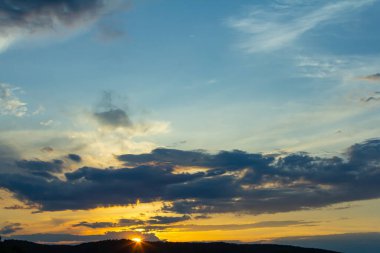 Güneş tepelerin arkasında batar gökyüzünü canlı portakallar ve sarılarla doldurur. Ufuk boyunca uzanan bulutlar nefes kesici bir akşam manzarası yaratıyor..